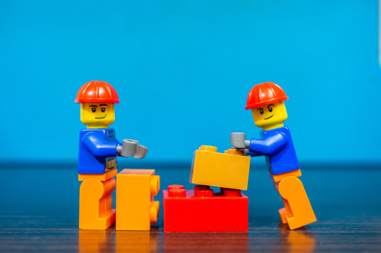 Two Lego construction workers build something together out of plastic bricks on December 14, 2019 in Poznan, Poland.